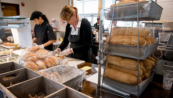 Two dining staff creating custom sandwiches for Ullman to Go