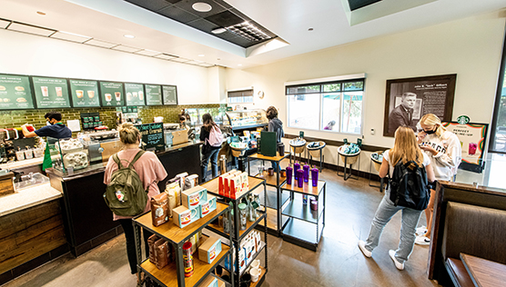 Students waiting for orders within the interior area of Starbucks along side goods for sale